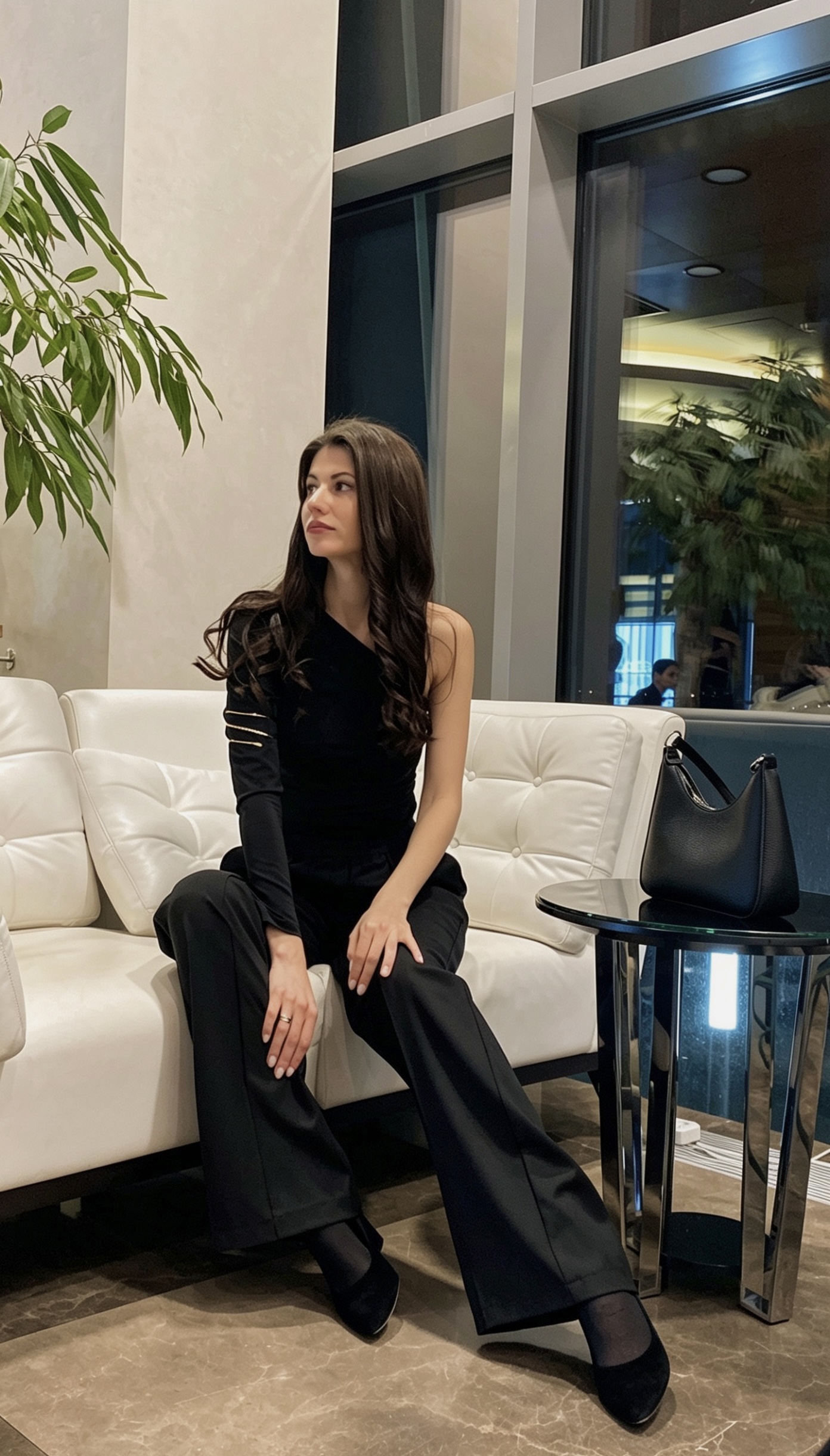 Lena seated indoors in an elegant black outfit